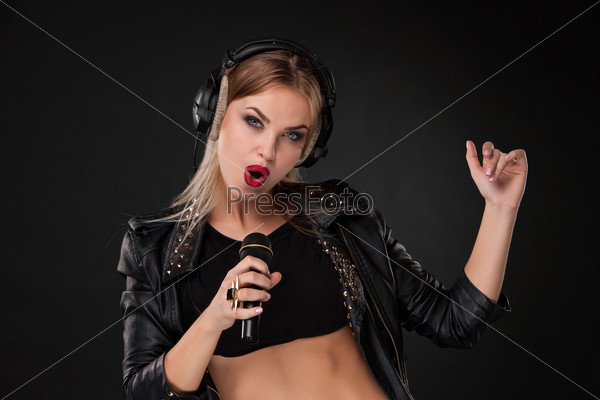 Женщина поет в микрофон на черном фоне