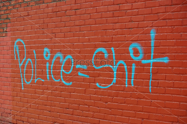 A red brick wall with graffiti spray painted on it
