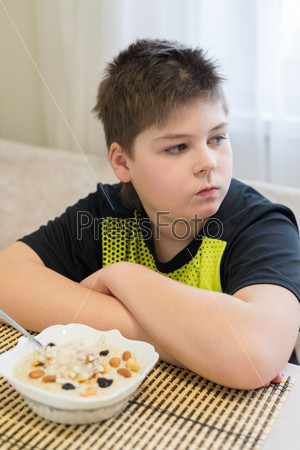 Teenager boy refuses to eat a oatmeal for breakfast
