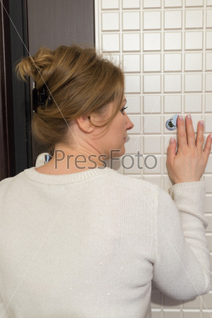 woman back looking to a peephole interior house hall