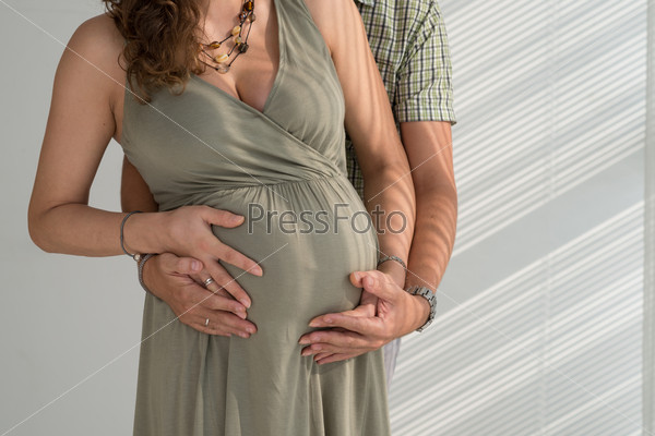 Cropped image of man hugging his pregnant wife from behind: parenthood concept
