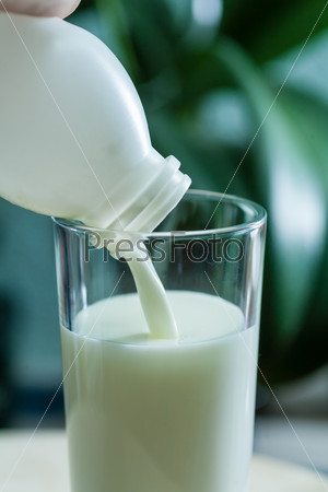 Молоко выливают в стеклянный стакан