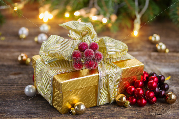 golden  christmas gift box with lights in background on wooden table