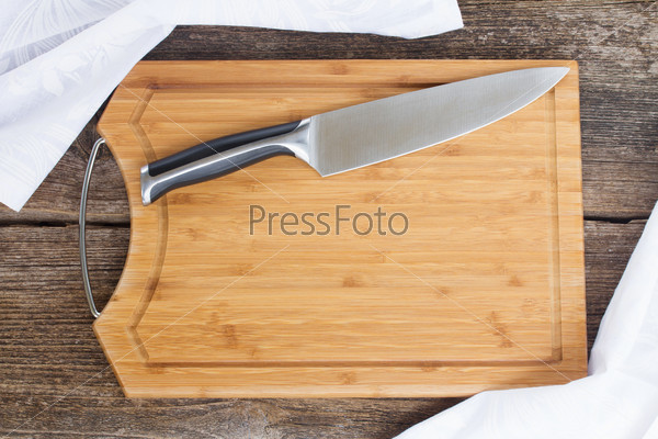 table with empty wooden cutting board, knife and cloth napkin