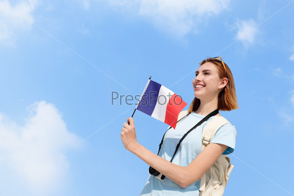 happy young travel woman holding France French flag with sky background, caucasian beauty