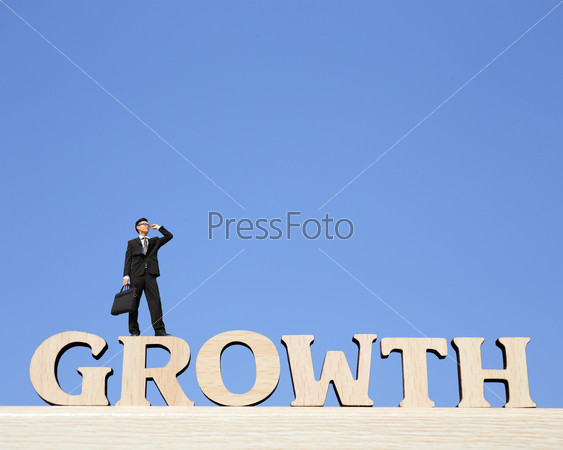 Growth business concept - business man stand on Growth text word and look sky, great for your design and business concept