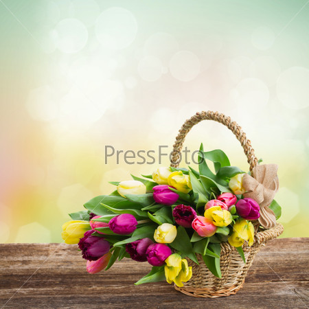 bunch of yellow and purple tulips in basket on wooden table border  with bokeh background