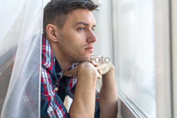 Handsome pensive man guy watching through the window concept sadness sorrow pain waiting