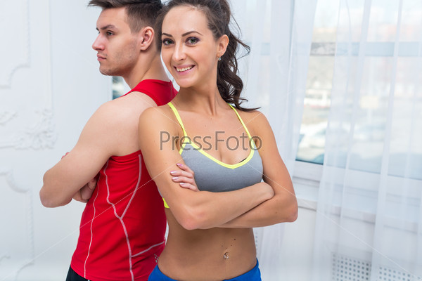 sporty couple friends slim athletic ambitious woman and confident man trainers team or coach client in sport hall gym standing arms crossed sportsmen professionals looking at camera.