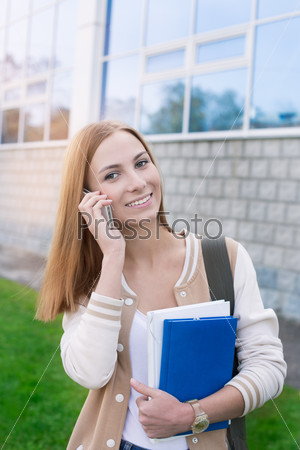 Student speaking on phone and holding books by left hand