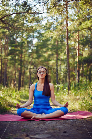Meditating woman relaxing in the forest in summer