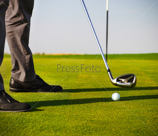 Male golfer putting, selective focus on golf ball