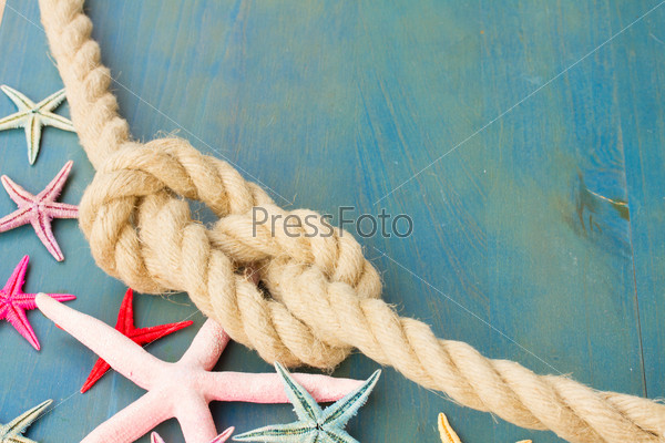 marine rope with starfish on blue wooden background with copys space