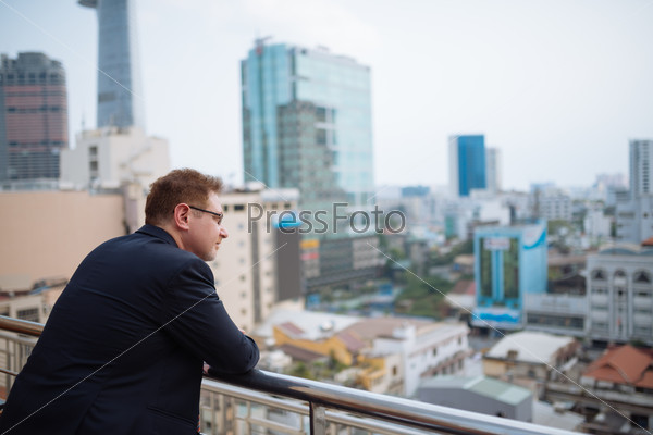 Businessman enjoying urban view from the balcony