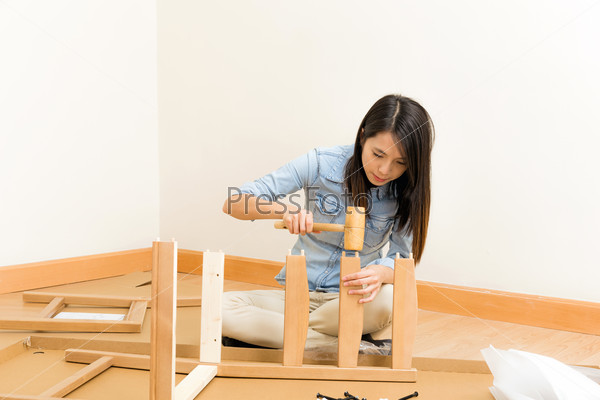 Asian woman assembling chair by hammer