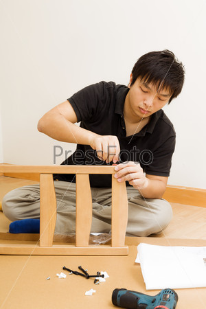 Asian man assembling chair at home