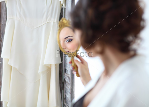 Gentle young bride looks in the mirror. Bridal morning