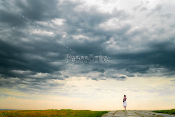 Girl looking at cloudy sky from bluff