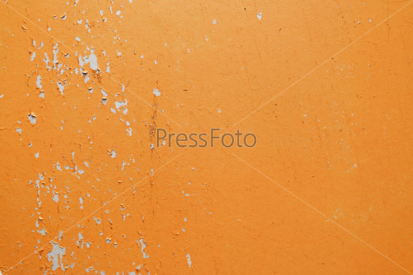 A fragment of the old wall, painted bright orange paint, cracked over time. Peeling paint texture.