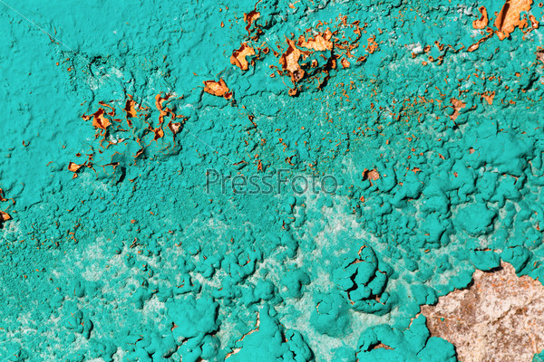 A fragment of the old wall, painted bright turquoise paint, cracked over time. Peeling paint texture.