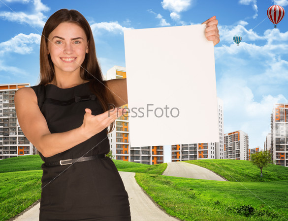 Estate agent holding blank poster with houses, road and green grass on background