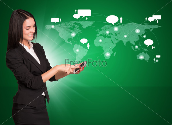 Smiling businesswoman in suit standing and using mobile phone on abstract green background