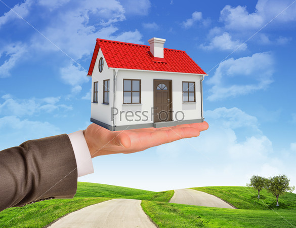 House in businessmans hand on nature background with road and trees
