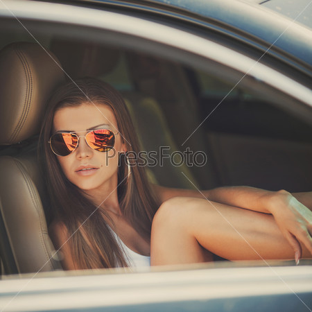 Portrait of beautiful sexy fashion woman model with bright makeup sitting in a car