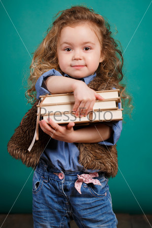 Education - funny little girl with books. Cute child in studio. Green background. Stack of books in hands