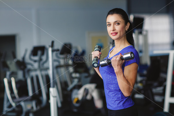 Strong woman weightlifting at the gym. Woman working out with dumbbells at a gym. Dumbbell bicep curl by a fitness girl. In good condition.