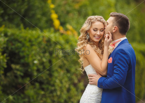 Wedding, Beautiful Romantic Bride and Groom Kissing and Embracing outdoors in nature. wedding kiss. Young newly married couple posing. Together