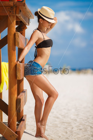 Relaxing beach woman enjoying the summer sun happy standing in sun hat at the beach. Summer. Vacation. Tropical beach