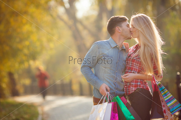 Couple with shopping bags in the street. Girl and man together shopping.