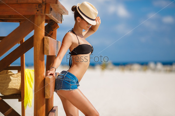 Relaxing beach woman enjoying the summer sun happy standing in sun hat at the beach. Summer. Vacation. Tropical beach