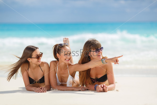 summer holidays, technology and beach concept - girls making self portrait on the beach. group of friends at the beach. summer holidays and vacation - girls in bikinis sunbathing on the beach