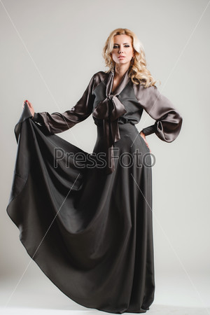 young beautiful caucasian brunette in gorgeous dress, motion shot. Pretty young lady in a fashion pose. Fashion photo of young magnificent woman. Studio fashion photo