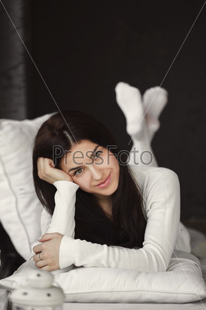 Young beautiful woman at home. Portrait of smiling beautiful young brunette woman at home. Beautiful and happy young woman sitting on the sofa over the domestic background