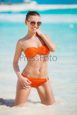 young beautiful woman in bikini on blue ocean background. Happy woman on the tropical beach. woman on beach with tropical suntan in virgin islands. Woman in bikini at tropical beach.