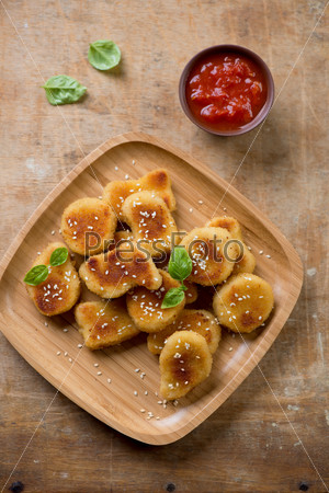 Sesame chicken nuggets with dipping sauce over rustic wooden background
