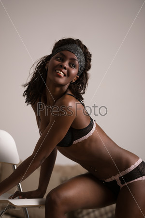 Beautiful african lady posing with chair at home wearing only sexy lingerie