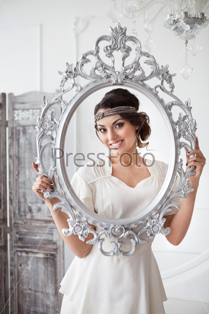 Portrait of the bride with big beautiful eyes on holding silver frame white background