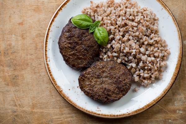 Buckwheat with meat cutlets, rustic wooden surface, above view