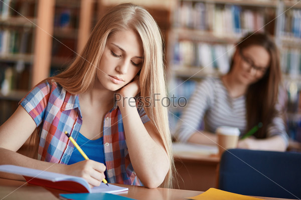 Serious girl making notes at lesson in college