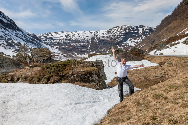 happy man on background mountains and snow-covered fjords. Norway in the spring