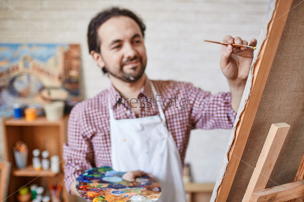 Male artist painting on canvas, stock photo