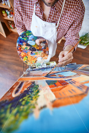 Male artist painting with oil paints on canvas