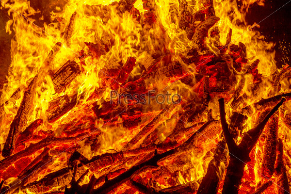 Burning campfire at night, combs flame as texture and background, strong branches burning trees of a forest fire