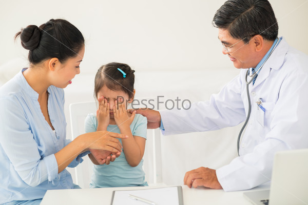Mother and pediatrician comforting little crying girl