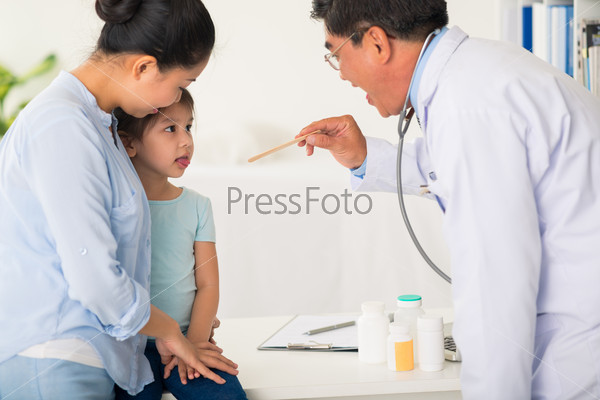 Doctor asking little girl to open mouth so he can examine her throat