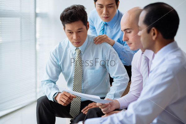 Group of shocked unhappy executives reading business document